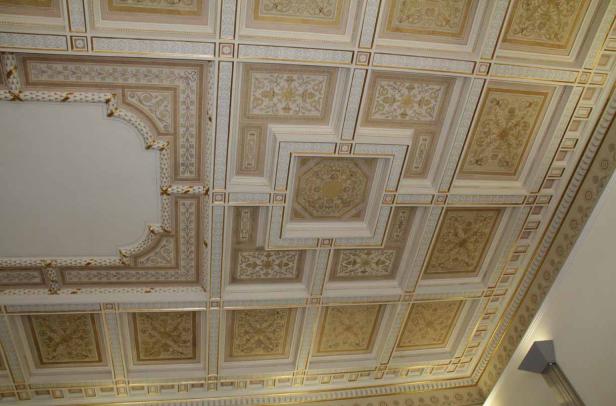 Eine kunstvoll verzierte Kassettendecke mit goldenen Akzenten.