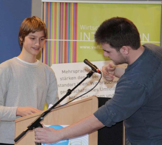 Zwei junge Männer stehen an einem Rednerpult vor einem Banner.