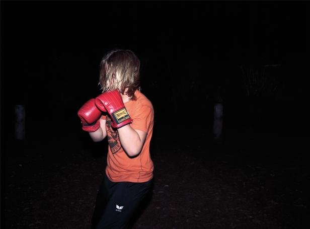 Eine Person mit Boxhandschuhen steht im Dunkeln.