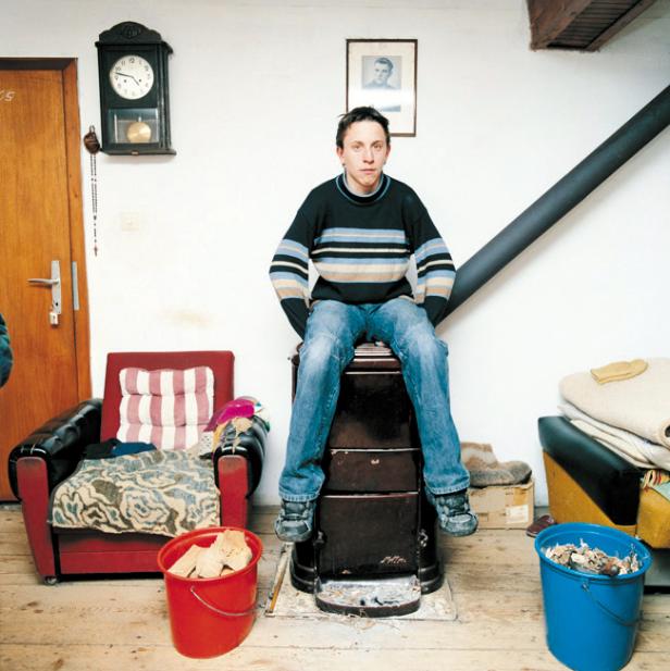 Ein Mann sitzt auf einem Ofen in einem Wohnzimmer.