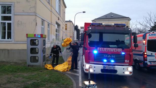 Feuerwehrleute hüllen gelbe Säcke neben einem Feuerwehrauto und einem Rettungswagen ein.