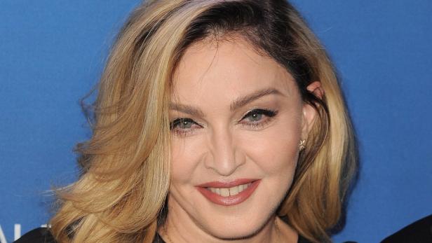 Nahaufnahme von Madonna mit blonden Haaren vor blauem Hintergrund.