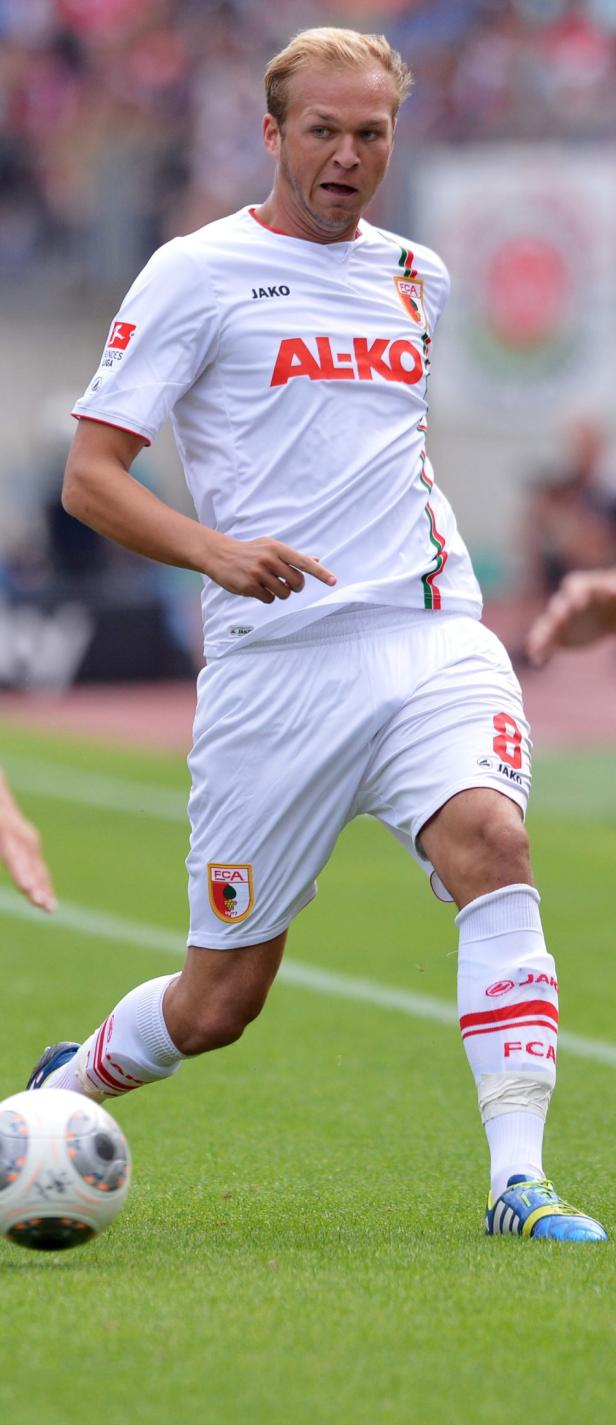Ein Fußballspieler des FC Augsburg im weißen Trikot am Ball.