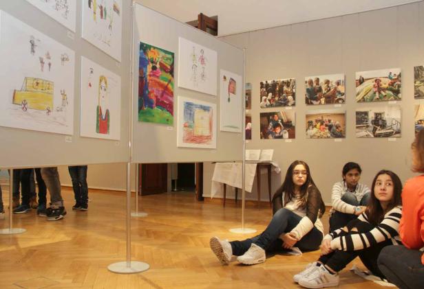 Mehrere Mädchen sitzen auf dem Boden und betrachten eine Kunstausstellung.