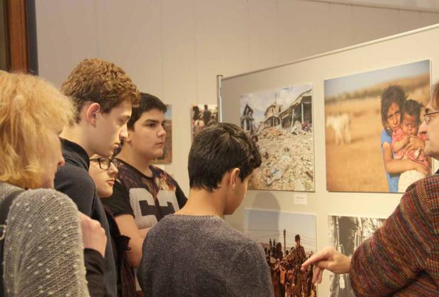 Eine Gruppe von Menschen betrachtet Fotos in einer Kunstausstellung.