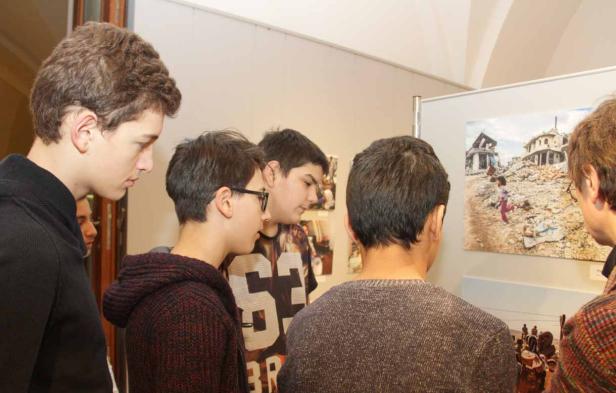 Eine Gruppe von Jugendlichen betrachtet Fotos in einer Kunstausstellung.