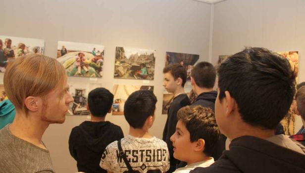 Eine Gruppe von Menschen betrachtet Fotografien in einer Kunstgalerie.