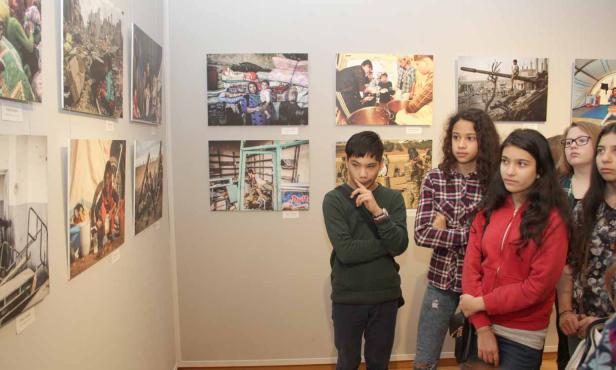 Eine Gruppe Jugendlicher betrachtet Fotos in einer Kunstausstellung.