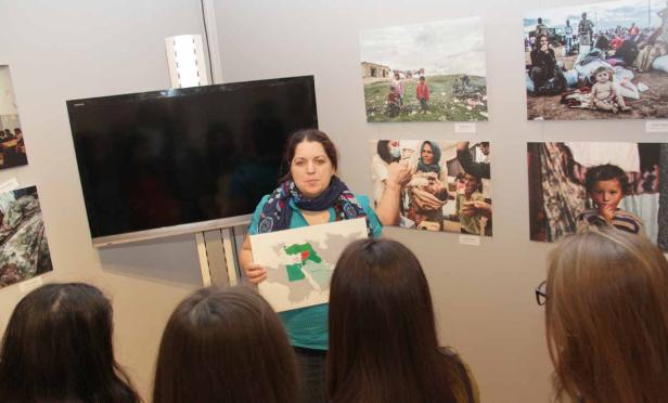 Eine Frau präsentiert eine Karte des Nahen Ostens vor einer Fotoausstellung.