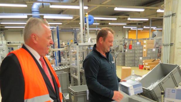 Zwei Männer arbeiten in einer Fabrikhalle an einer Produktionslinie.