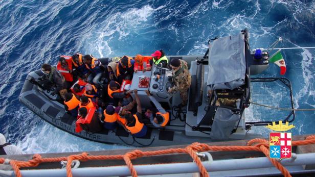 Ein Schlauchboot voller Menschen wird von einem Schiff der italienischen Marine gerettet.