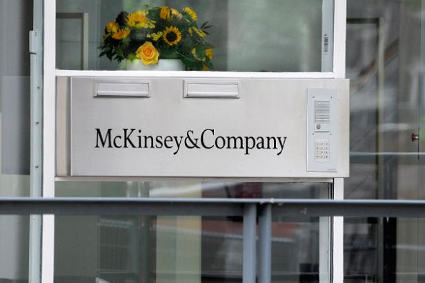 Das Schild von McKinsey & Company an einem Gebäude mit einem Blumenarrangement darüber.