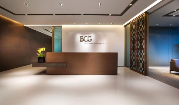 Der Empfangsbereich von BCG (The Boston Consulting Group) mit einem Holzschreibtisch und gelben Blumen.