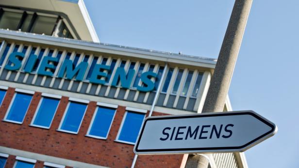 Ein Wegweiser mit dem Siemens-Logo vor einem Siemens-Gebäude.