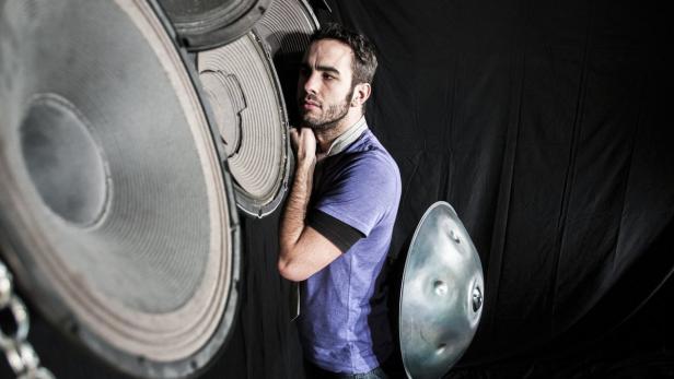 Ein Mann steht neben großen Lautsprechern und einem Hang-Instrument.