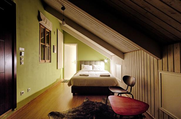 Ein Schlafzimmer mit Dachschräge, grün gestrichenen Wänden und einem Doppelbett.