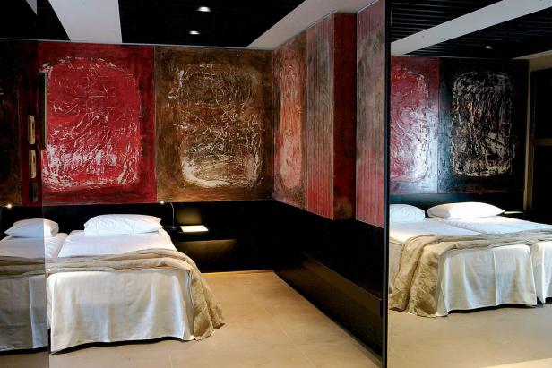 Ein Hotelzimmer mit zwei Betten und abstrakten Gemälden an der Wand.