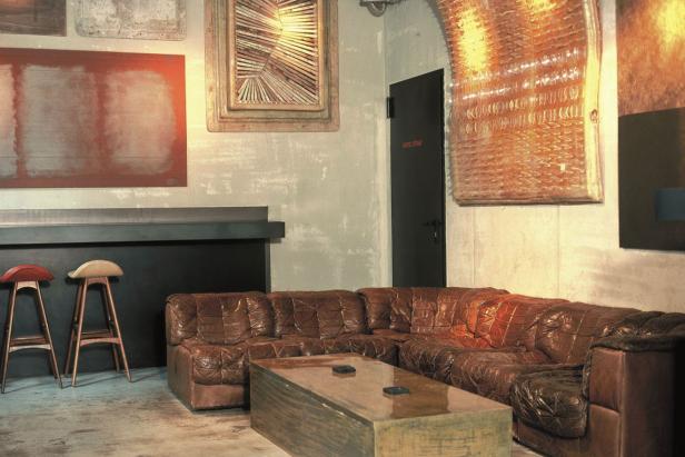 Ein braunes Ledersofa und ein Couchtisch in einem Raum mit Kunstwerken an den Wänden.