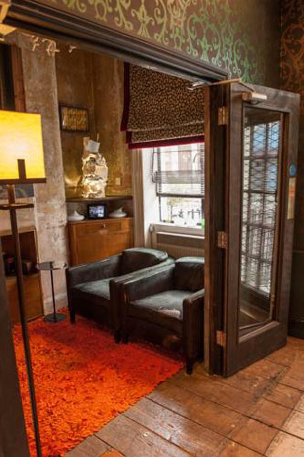 Ein Raum mit zwei Sesseln, einem orangefarbenen Teppich und einer gläsernen Tür.