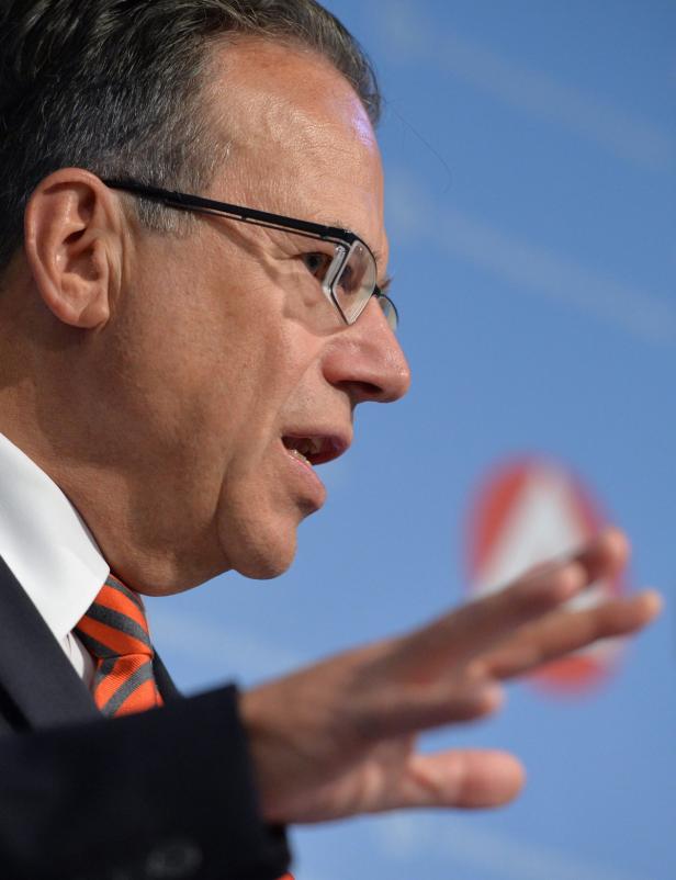 Ein Mann mit Brille und Krawatte gestikuliert vor blauem Hintergrund.