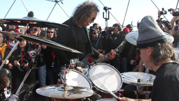 Metallica spielt vor einer Menschenmenge, Kirk Hammett mit Gitarre und Lars Ulrich am Schlagzeug.