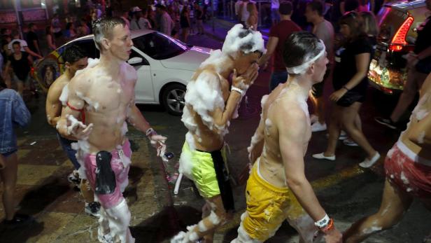 Mehrere junge Männer sind bei einer Schaumparty auf der Straße zu sehen.