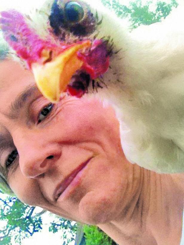 Eine Frau macht ein Selfie mit einem weißen Huhn.