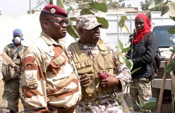 Mehrere uniformierte Personen stehen im Freien.