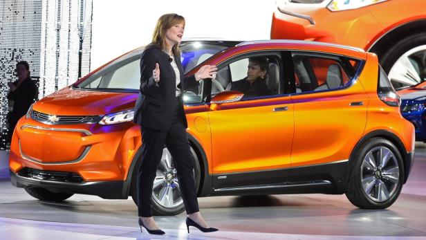 Eine Frau präsentiert ein orangefarbenes Chevrolet-Konzeptfahrzeug auf einer Automobilmesse.
