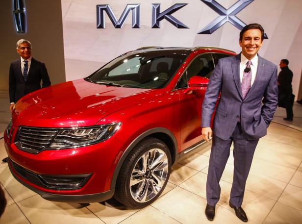 Ein roter Lincoln MKX wird auf einer Automobilmesse von zwei Männern im Anzug präsentiert.