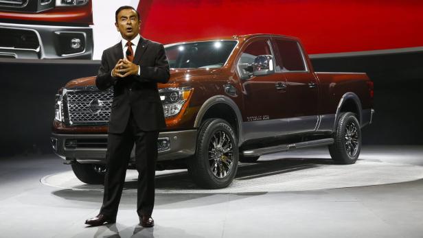 Ein Mann in einem Anzug steht vor einem braunen Nissan Titan Pickup-Truck.