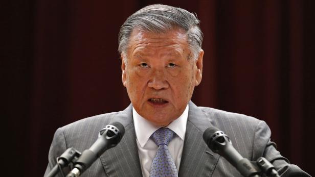 Ein Mann im Anzug spricht vor Mikrofonen.