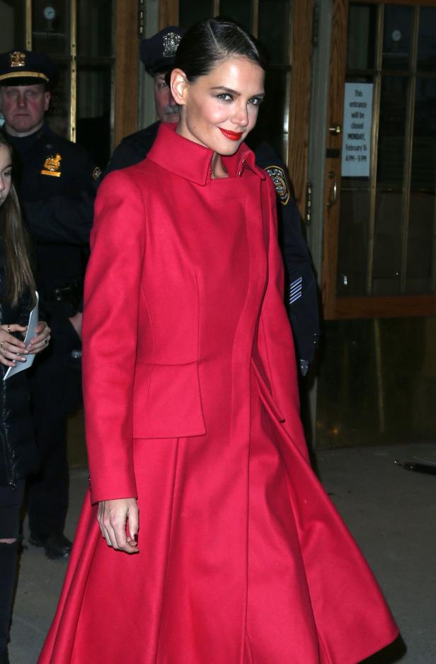 Katie Holmes trägt einen roten Mantel vor einem Gebäude.