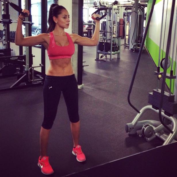 Eine Frau trainiert im Fitnessstudio mit einer Kabelzugmaschine.