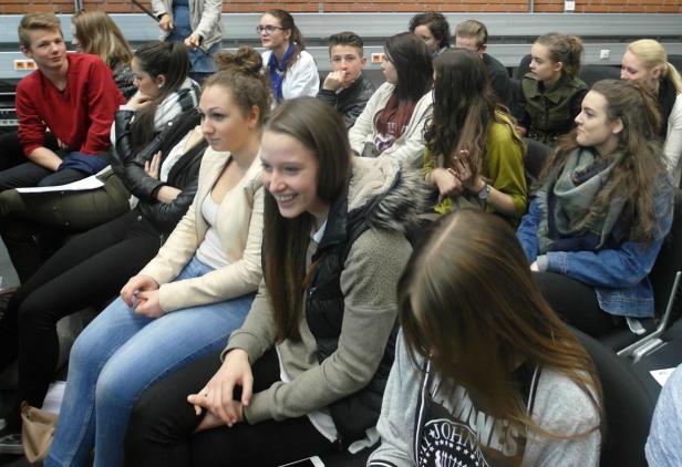 Eine Gruppe junger Leute sitzt in einer Reihe und schaut in die gleiche Richtung.