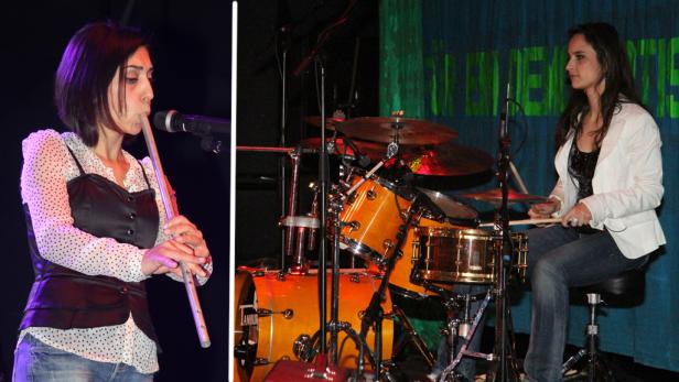 Eine Frau spielt eine Flöte, während eine andere Frau Schlagzeug spielt.