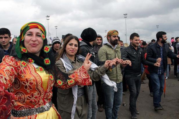 Eine Gruppe von Menschen tanzt traditionelle kurdische Tänze im Freien.