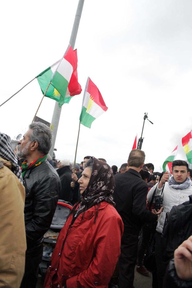 Eine Menschenmenge demonstriert mit kurdischen Flaggen.