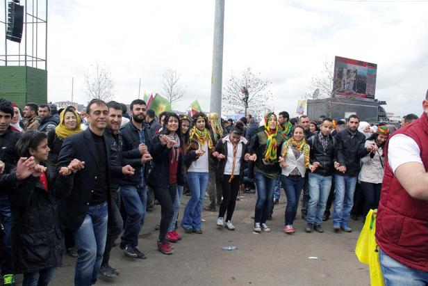 Eine Gruppe von Menschen tanzt Händchen haltend auf einer Straße.