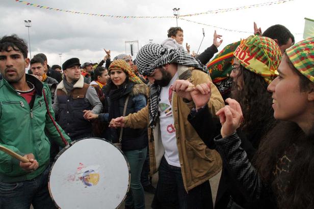 Eine Gruppe von Menschen tanzt und feiert mit einer Trommel im Freien.