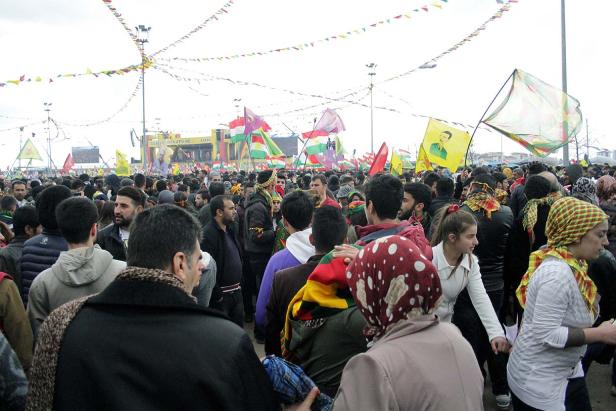 Eine große Menschenmenge mit kurdischen Flaggen und Bannern bei einer Kundgebung.
