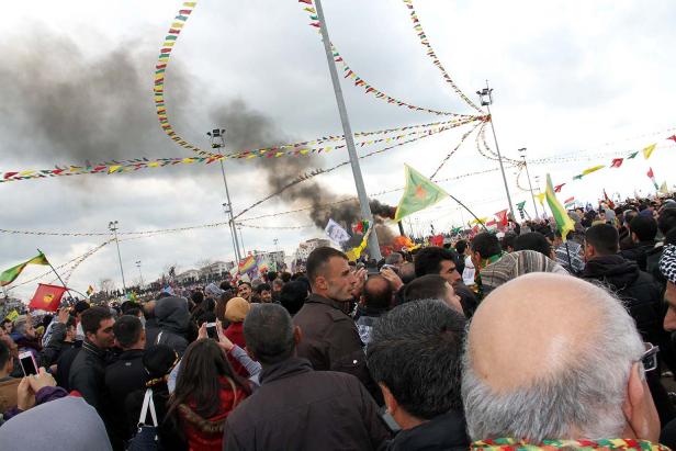 Eine Menschenmenge feiert mit Flaggen und Rauch im Hintergrund.