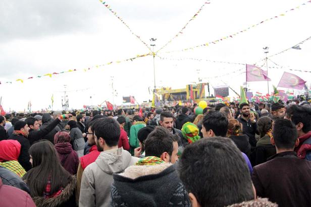 Eine große Menschenmenge versammelt sich unter bunten Flaggen und Bannern.