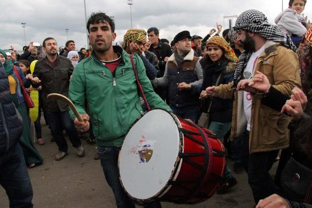 Ein Mann spielt eine große Trommel, während eine Gruppe von Menschen tanzt.