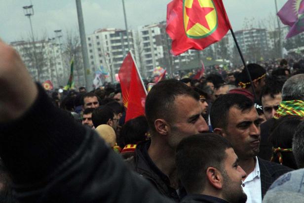 Eine Menschenmenge demonstriert mit kurdischen Flaggen in einer Stadt.