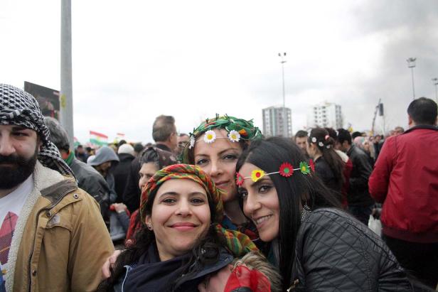 Eine Gruppe von Frauen mit Blumenkränzen und traditionellen Tüchern auf einer Kundgebung.