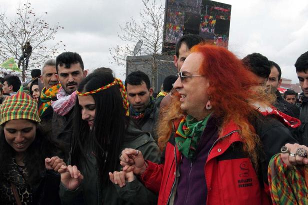 Eine Gruppe von Menschen hält Hände bei einer Versammlung im Freien.