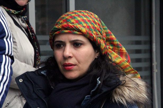 Eine Frau mit einem bunten Kopftuch und dunkler Jacke.