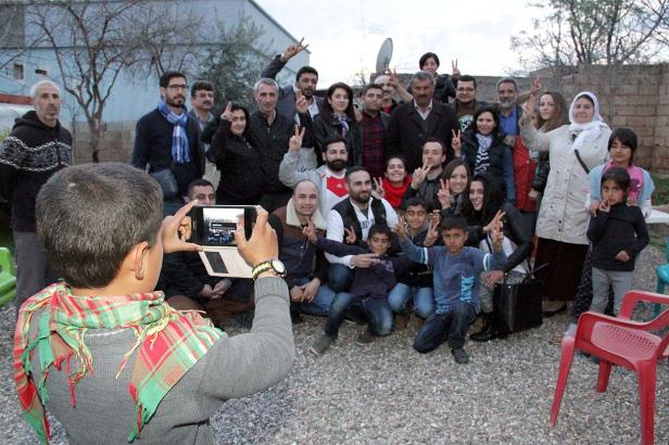 Eine Gruppe von Menschen posiert für ein Foto, das ein Kind mit einem Smartphone aufnimmt.