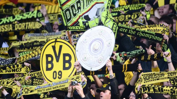 Borussia Dortmund Fans feiern mit Schals und der Meisterschale.